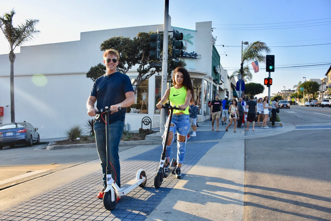 Two Simply Brilliant riders cruising through a sunny city crosswalk