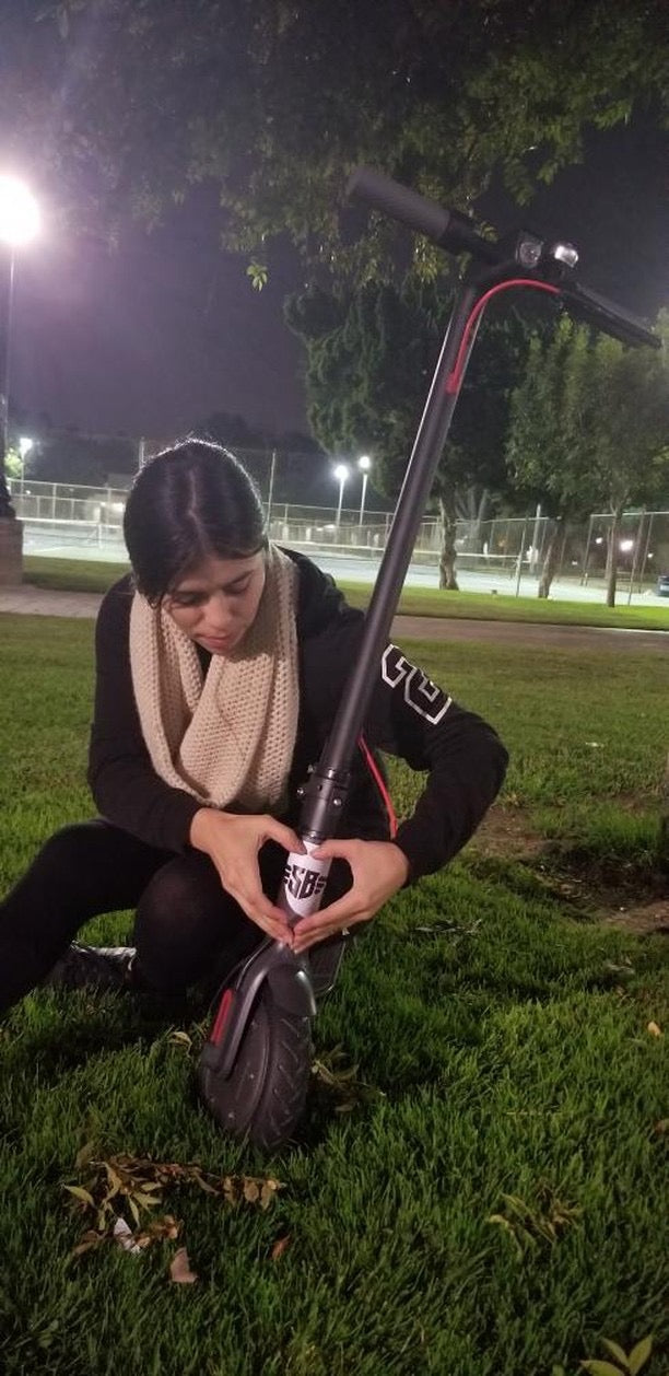 A rider adjusting the front badge of a scooter on the grass at night