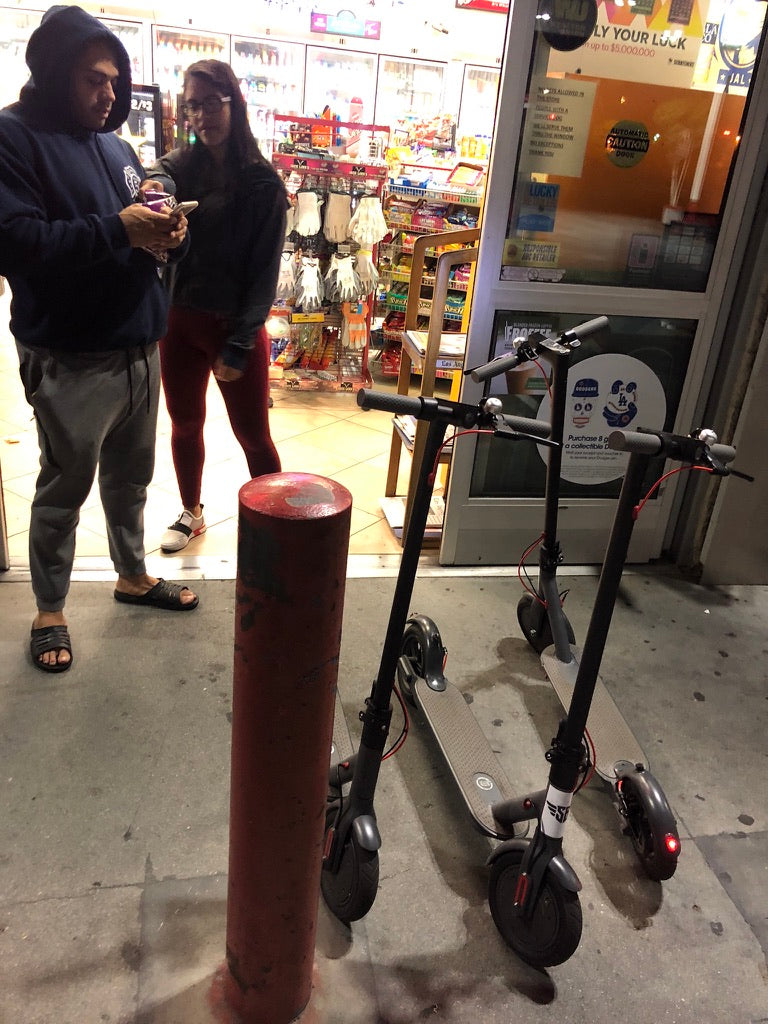 Two scooters parked outside a late-night convenience store